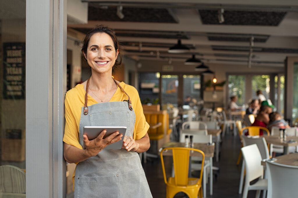 entrepreneur standing in front of her LLC store with a tablet smiling 