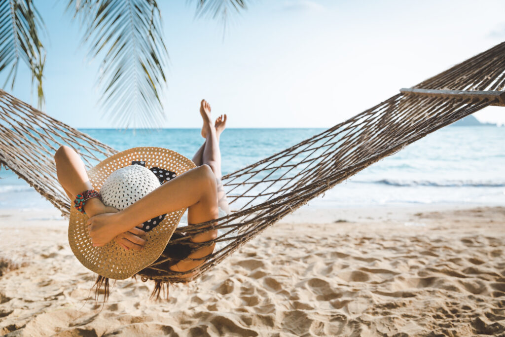 woman on a florida beach relaxing on a hammock with a palm tree above her