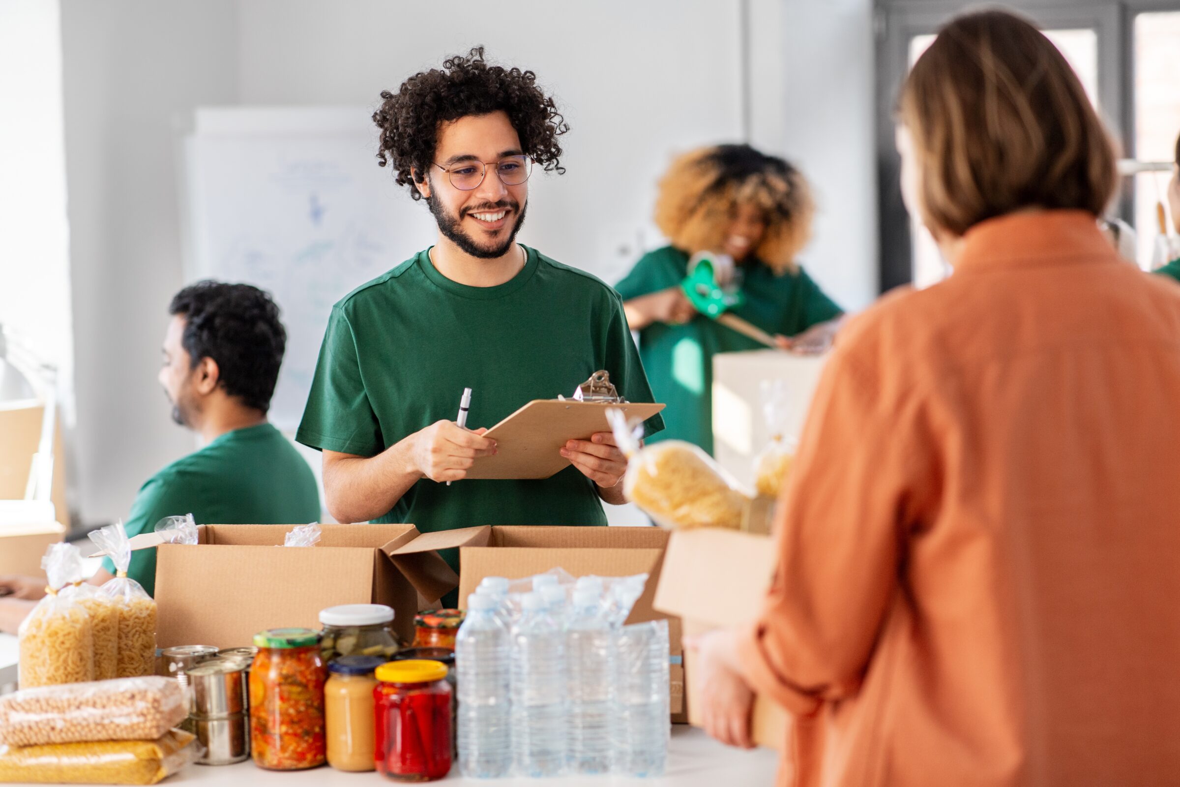 man with curly hair working at a nonprofit in Colorado with jars and food and boxes in front of him