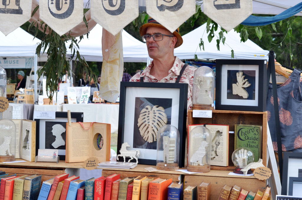 man standing at a art stand with book art 