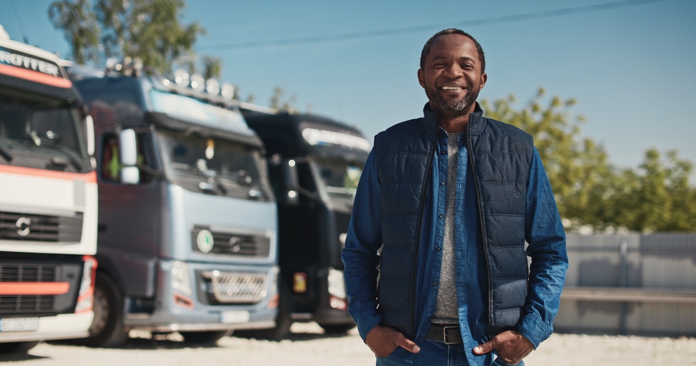 smiling man infront of his trucking company that he owns