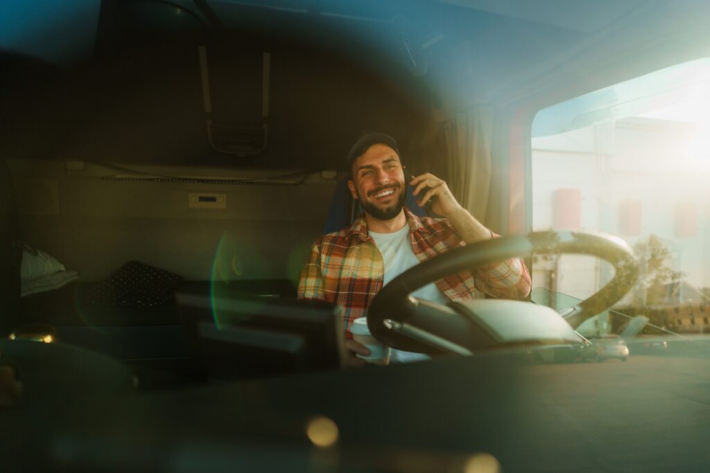 man smiling inside his big truck on the phone 