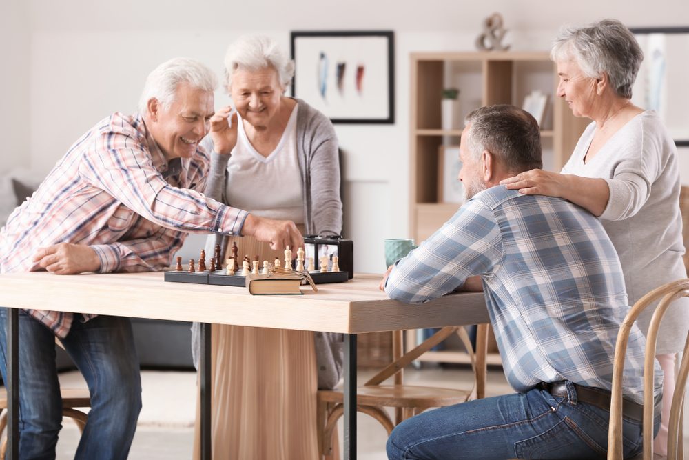 seniors in a senior living facility playing chess and smiling