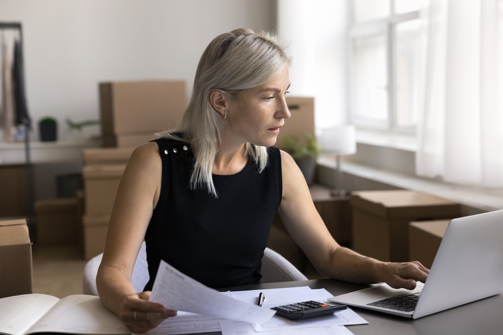 blonde woman with boxes in the background of her business doing paperwork and researching corporate transparency act 2024 exemptions