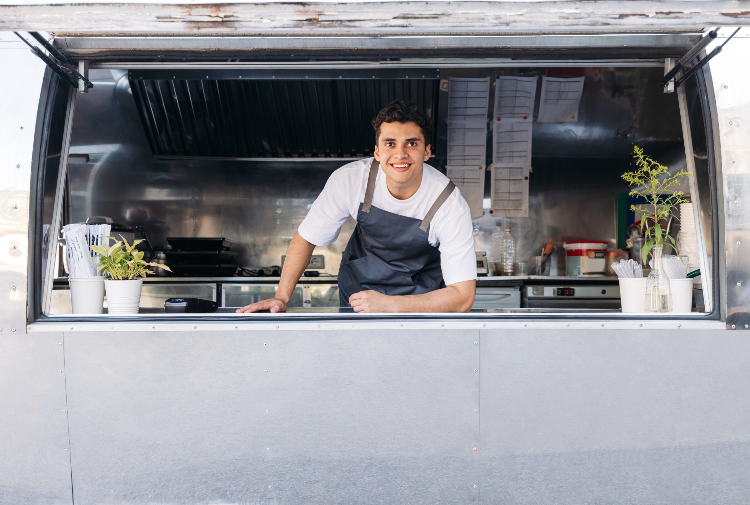 small business owner at his window shop smiling with plants on the sill 